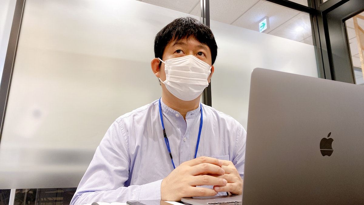 パソコンを前にして導入のきっかけについて説明している開発リーダーの角田さんの写真